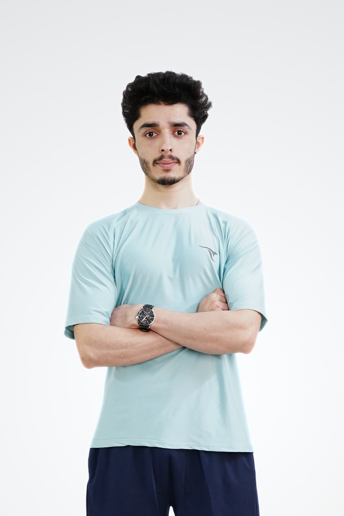 Man wearing a light blue t-shirt and navy shorts with a brand logo on a white background